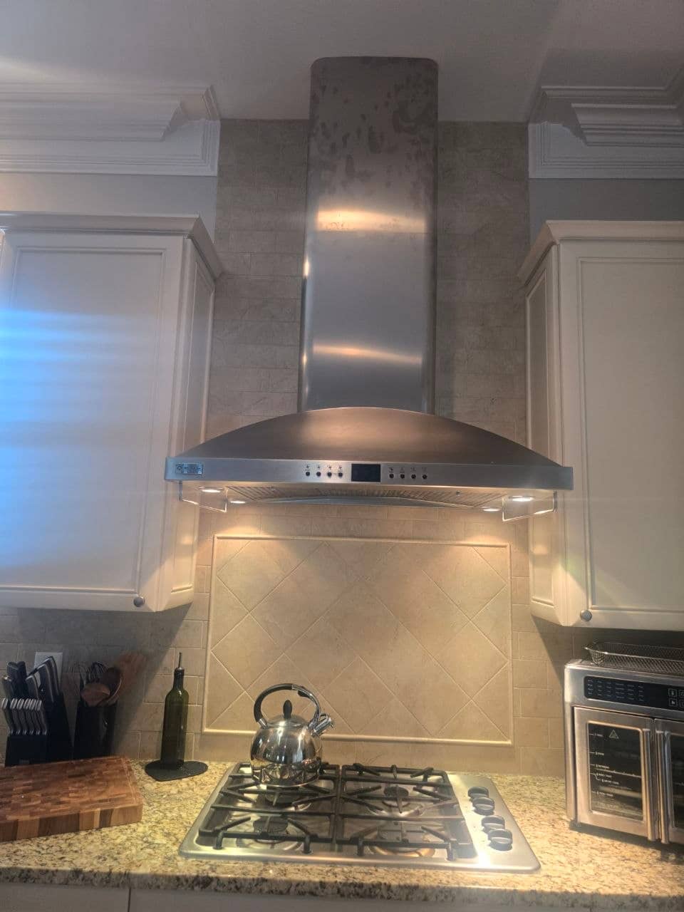 The same kitchen range hood after repair with its cooktop lights on