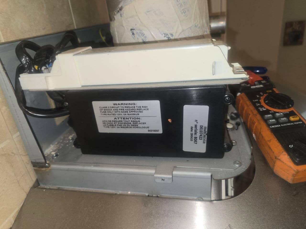 Lighting transformer and control housing exposed during the range hood repair