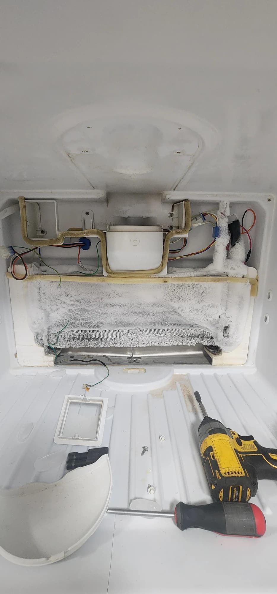 Frost-covered evaporator inside the GE refrigerator freezer before the Charlotte repair