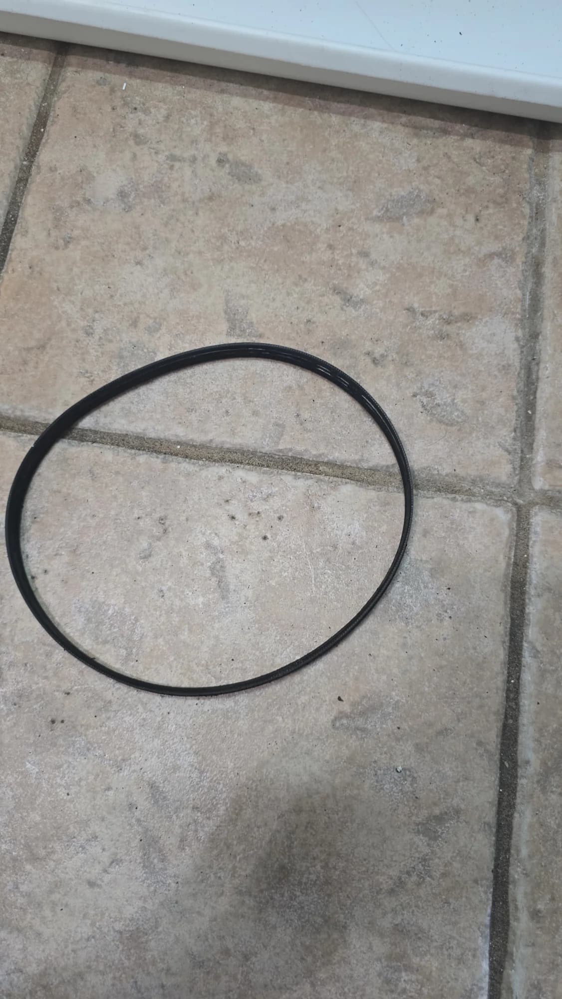 Removed old GE washer drive belt lying on the floor